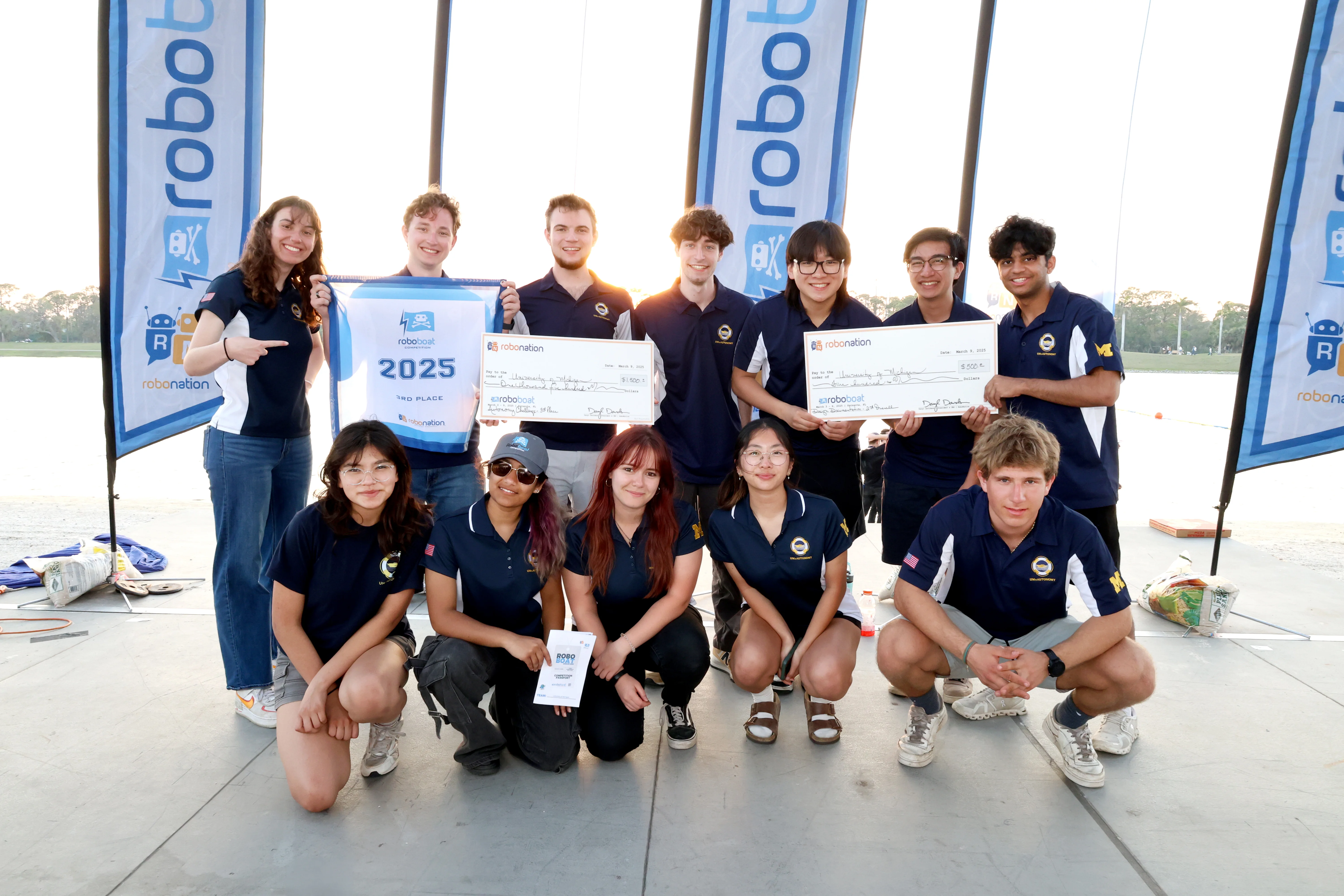 UM::Autonomy members pose on-stage with a judge holding a banner reading "2023 3rd place design documentation"